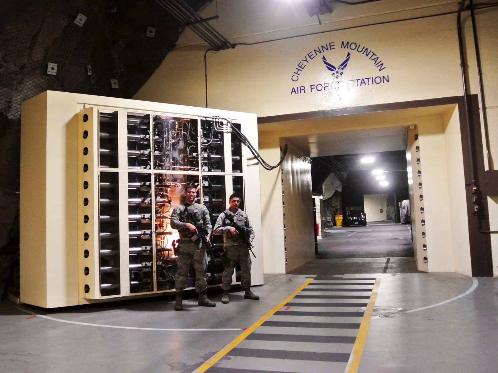 Two armed airmen beside a large equipment enclosure at a tunnel intersection in Cheyenne Mountain