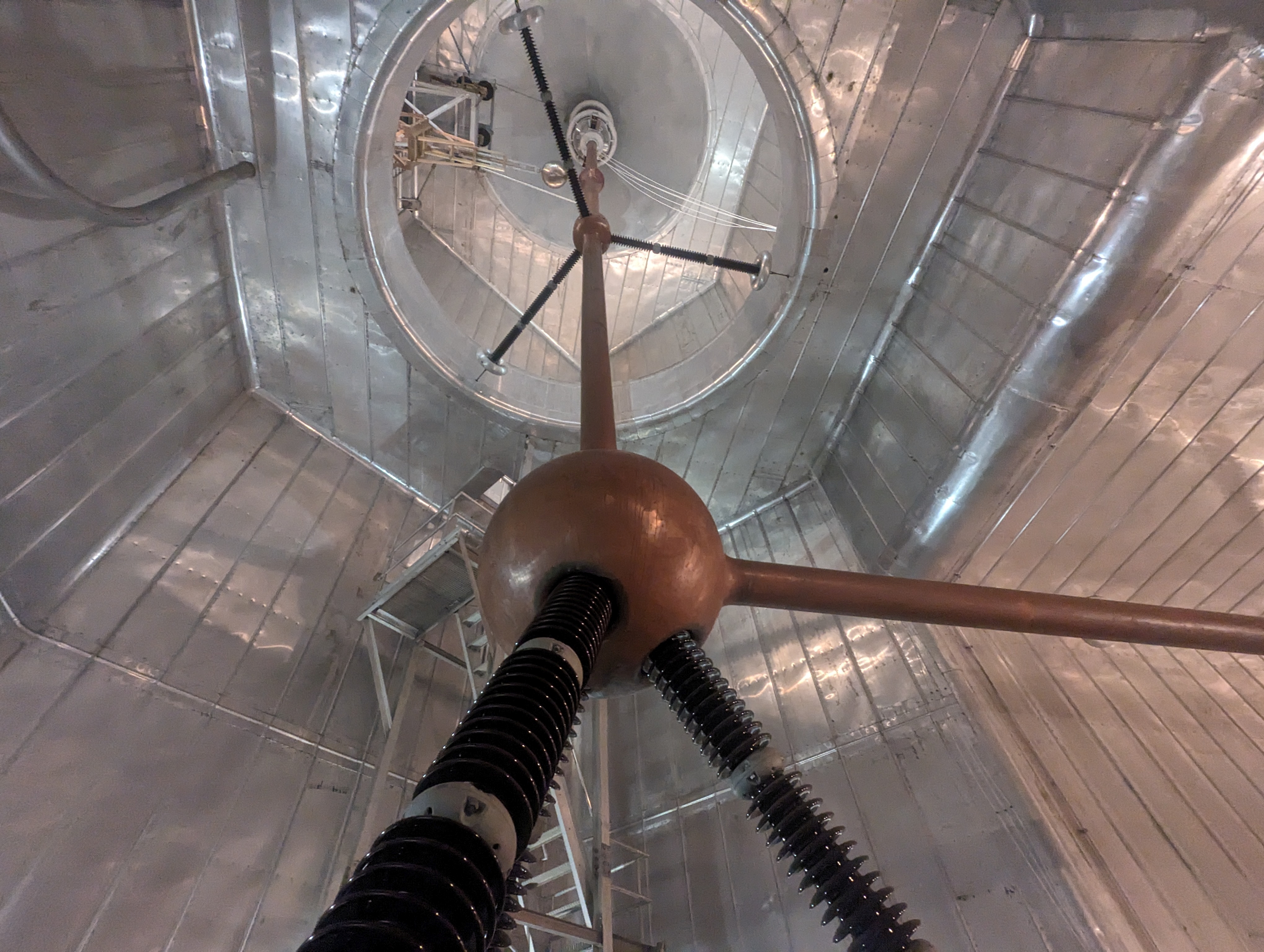 Interior of a large metal-lined hall with a copper sphere and insulator
