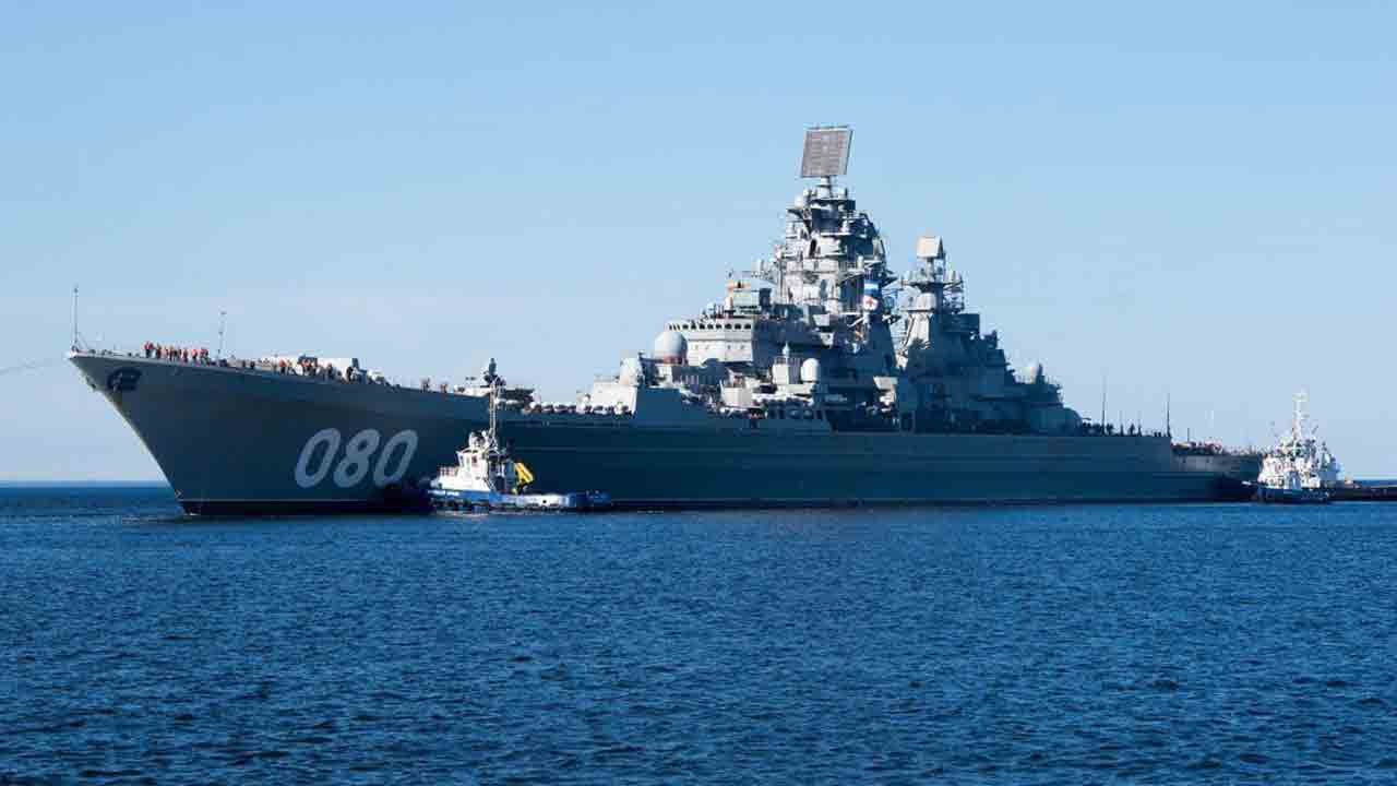 Kirov-class cruiser with hull number 080 at sea, two tugs alongside, crew on the forecastle